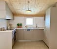 Modern kitchen with tile flooring, white cabinets, built-in appliances, ceiling fan, plants, and a window