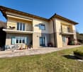 2 story house, beige exterior, blue shutters, 2 balconies, garden, patio with table and chairs