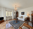 white walls, chandelier, fireplace, white couch, coffee table, rug, TV, wooden furniture, lamp, picture frame, radiator