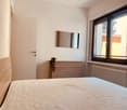 Bedroom with bed, wooden headboard, wooden dresser, mirror, window, radiator, plant