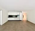 Empty room with white walls, tiled floor, white kitchen cabinets, black countertop, open door