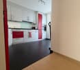 Modern kitchen with white cabinets, red accents, black tiled floor, wooden tiles on the side, kitchen appliances