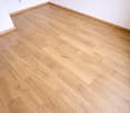 Empty room with hardwood floor, white walls, power outlet on wall.