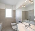 modern bathroom with bathtub, bidet, toilet, sink, mirror, and wall-mounted lights
