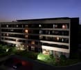 Modern apartment building, multiple floors, balconies, underground parking, garden area