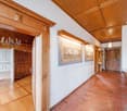 wooden floor, wooden ceiling, chandelier, two paintings on the wall, wooden doors