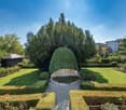 well-manicured garden with a central fountain, neatly trimmed hedges, and a variety of plants and flowers