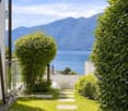 Pathway leading to a lake view, surrounded by greenery, mountains in the background
