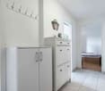 hallway with white cabinets, a coat rack, and a door leading to the bedroom and bathroom