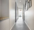 Gray floor, white walls, a built-in bench, a hanging mirror, photo frames on the wall, and a light fixture on the ceiling.