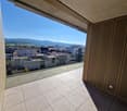 Balcony with tiled floor, glass railing, view of the city and mountains