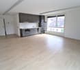 empty room, wooden floor, white walls, kitchen with appliances, large window