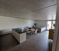 modern kitchen with island, dining table, living room with couch, open floor plan, white walls, tiled floor