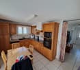 kitchen with wooden cabinets, tiled floor, dining table, sink, oven, microwave, dishwasher, washing machine