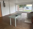 empty room, wooden floor, white table, large windows, view of outside