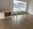 empty room, wooden floor, large window, table, bags, rug