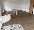 empty room, wooden floor, white walls, glass door, small table, rug, bottle, stuffed toy