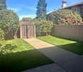 well-maintained garden with a paved walkway, lush green grass, and a wooden gate leading to the entrance
