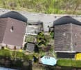 Two houses, brown roofs, driveway, blue truck, swimming pool, garden, trees, grass