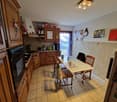 Spacious kitchen with wooden cabinets, tile flooring, dining table, and various kitchen appliances including a dishwasher