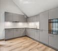 modern kitchen, gray cabinets, wooden floor, sink, oven, dishwasher, washing machine