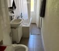 White bathroom with a toilet, sink, bathtub, towel rack, and a washing machine