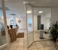 empty office room with tiled floor, glass walls, wooden desk, reception desk, chairs, plant
