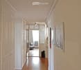 Hallway with white walls, wooden floors, and cabinets
