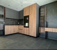 modern kitchen with wooden cabinets, black marble walls, sink, oven, dishwasher, washing machine, tiled floor