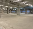 open space, concrete floor, high ceiling, multiple pillars, windows