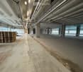 Empty hall way, concrete floor, steel beams, pallets, windows