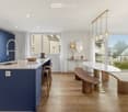Open kitchen, blue cupboards, marble countertop, modern island, large windows, wooden floor