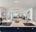 open kitchen with wooden bowl, induction stove, sink, modern faucet, marble counter, blue cabinets, large windows, balcony with railing, table, round lamp