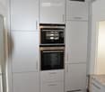 White cabinets, stainless steel handles, brown tiled floor, double oven, dishwasher, modern lighting