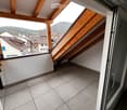 Balcony with wooden beams, tiled floor, open sliding door, view of the mountains