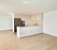 modern kitchen with white cabinets, tiled floor, stainless steel appliances, island with sink and faucet