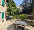 Stone wall, stone bench, green shutters, stone floor, trees, plants, bushes