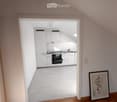 Empty room with white walls, wooden floor, white kitchen with oven and sink, picture frame on the wall