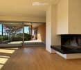 Living Room. Modern living room with light wooden flooring, large glass doors leading to a patio, and a built-in fireplace.