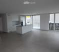 Kitchen. Modern kitchen with white cabinets, a central island, and large windows leading to a balcony.
