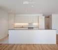 Modern kitchen with white cabinets, granite countertop, and wooden flooring.