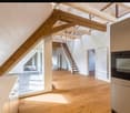 Open-plan kitchen and living area with wooden beams, light wooden flooring, and a staircase leading to an upper level.