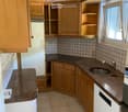 Compact kitchen with wooden cabinets, granite countertops, electric stove, sink, and refrigerator.