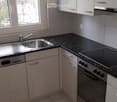 Modern kitchen with white cabinets, granite countertops, stainless steel sink, oven, and dishwasher.