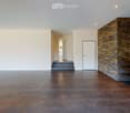 Open living area with a staircase, brick accent wall, tiled flooring, white walls, doorway, metal shelves