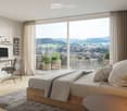 Modern bedroom with a large bed, nightstand, desk, and a scenic view of the countryside through large windows. The room features a sleek desk setup with a computer and chair, shelves with picture frames, and potted plants on the balcony.