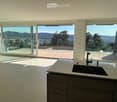 Modern kitchen with large windows offering a scenic view, featuring a sink and faucet.