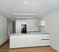 White cabinets, wooden floor, kitchen sink, electric stove, white ceiling, white walls, integrated lighting, white radiator.