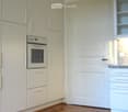 Modern kitchen with white cabinets, built-in oven, and granite countertop.