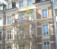Multi-story residential building with brick and white facade, multiple windows, balconies, and decorative architectural details.